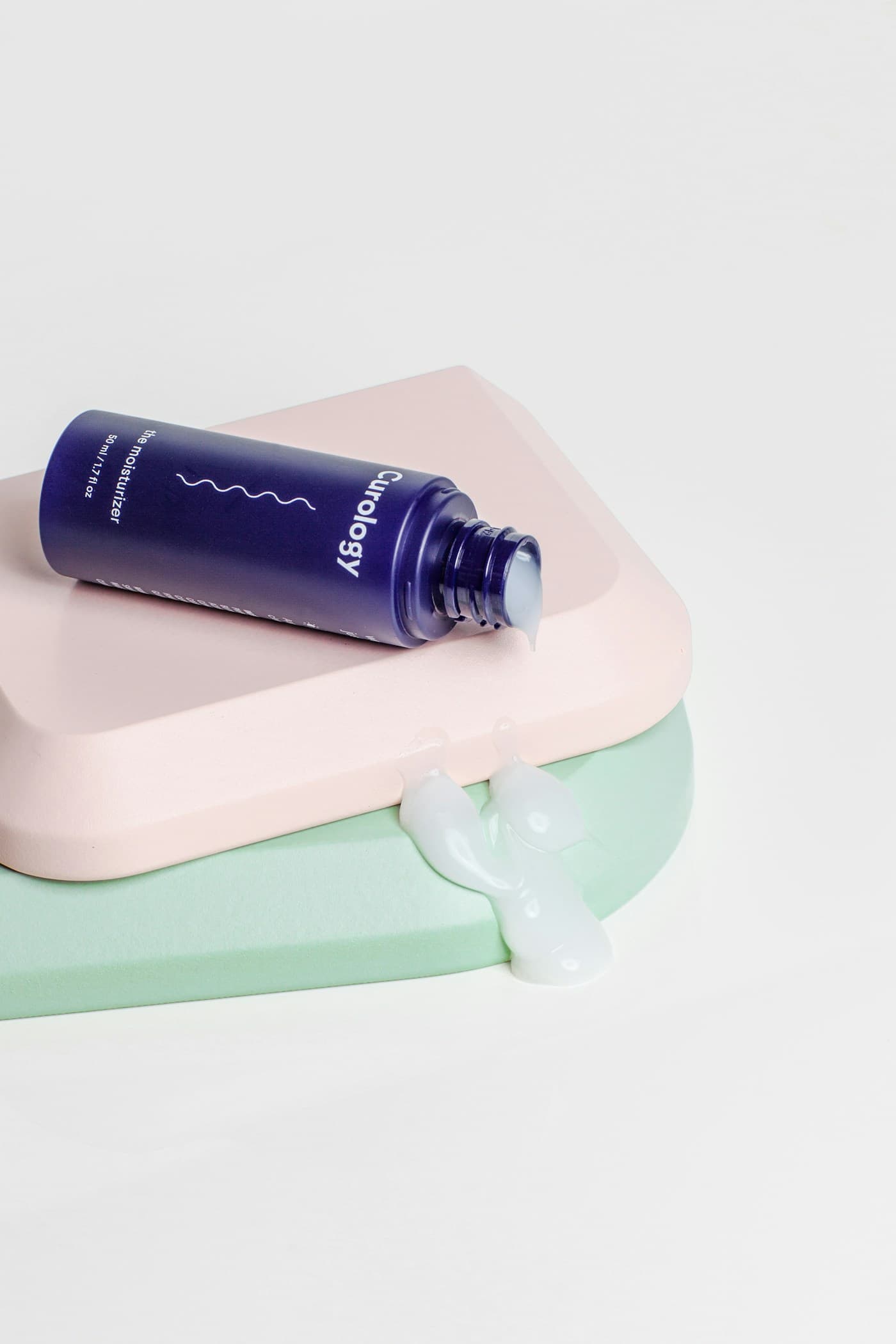 A moisturizer bottle on pastel display blocks